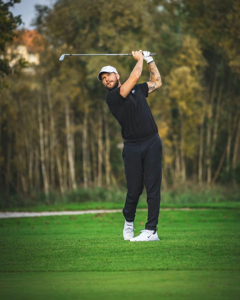 a man swinging a golf club on top of a green field