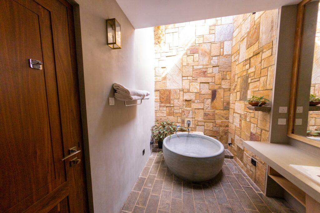 white ceramic bathtub beside brown brick wall