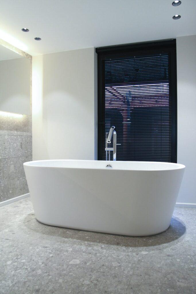 white ceramic bathtub near window